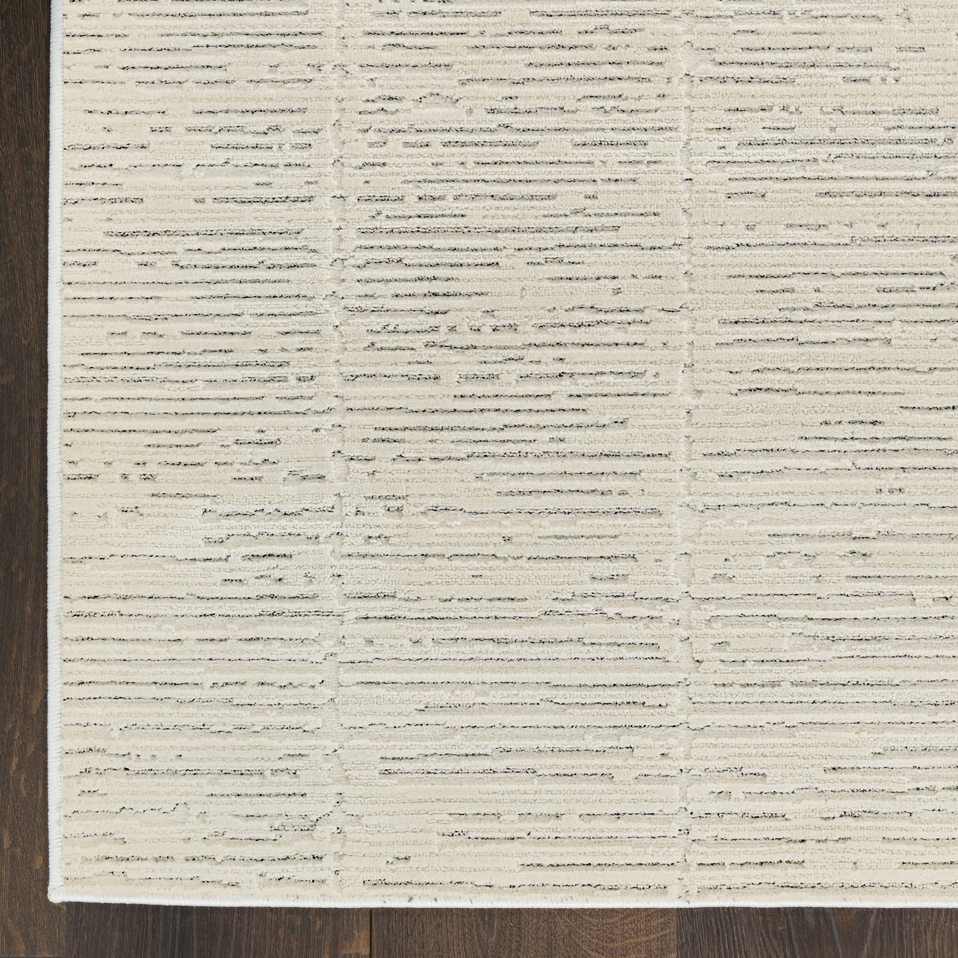Cream textured area rug with raised horizontal stripes on dark wood floor.