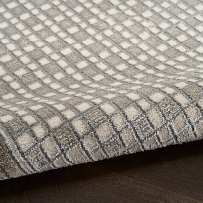 Beige and gray checkered woven rug with a soft loop pile, folded edge on dark wood floor.