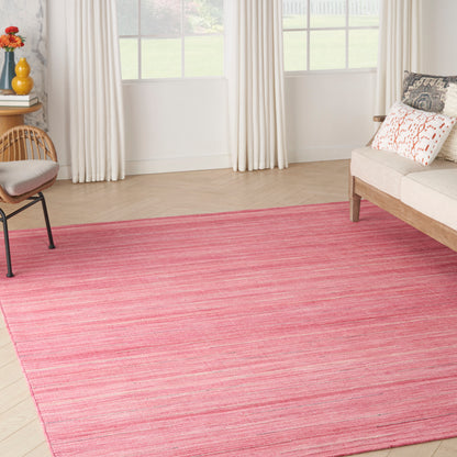 Pink striped rug on light wood floor in bright living room with white curtains, cream sofa, and wooden chair.