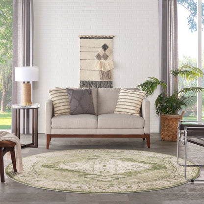 Cozy living room with light gray sofa, striped beige cushions, circular green rug, wall tapestry, and potted plant.