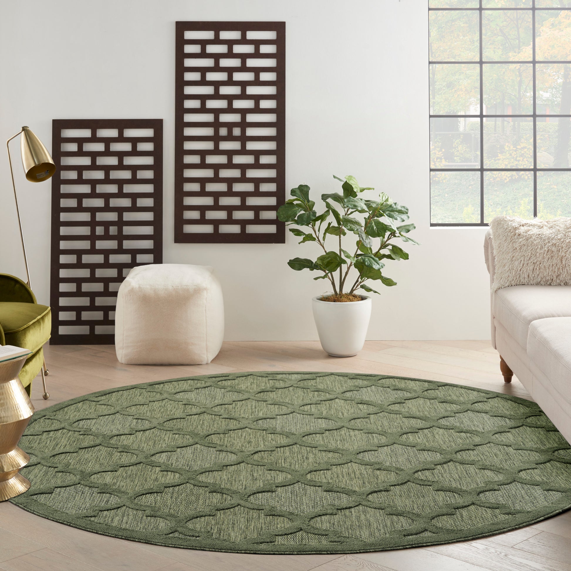 Round green rug with lattice pattern in a bright living room with white walls, plant, and lounge seating.