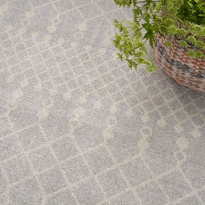 Soft gray rug with beige geometric lattice pattern; woven wicker basket with green plant in the corner.