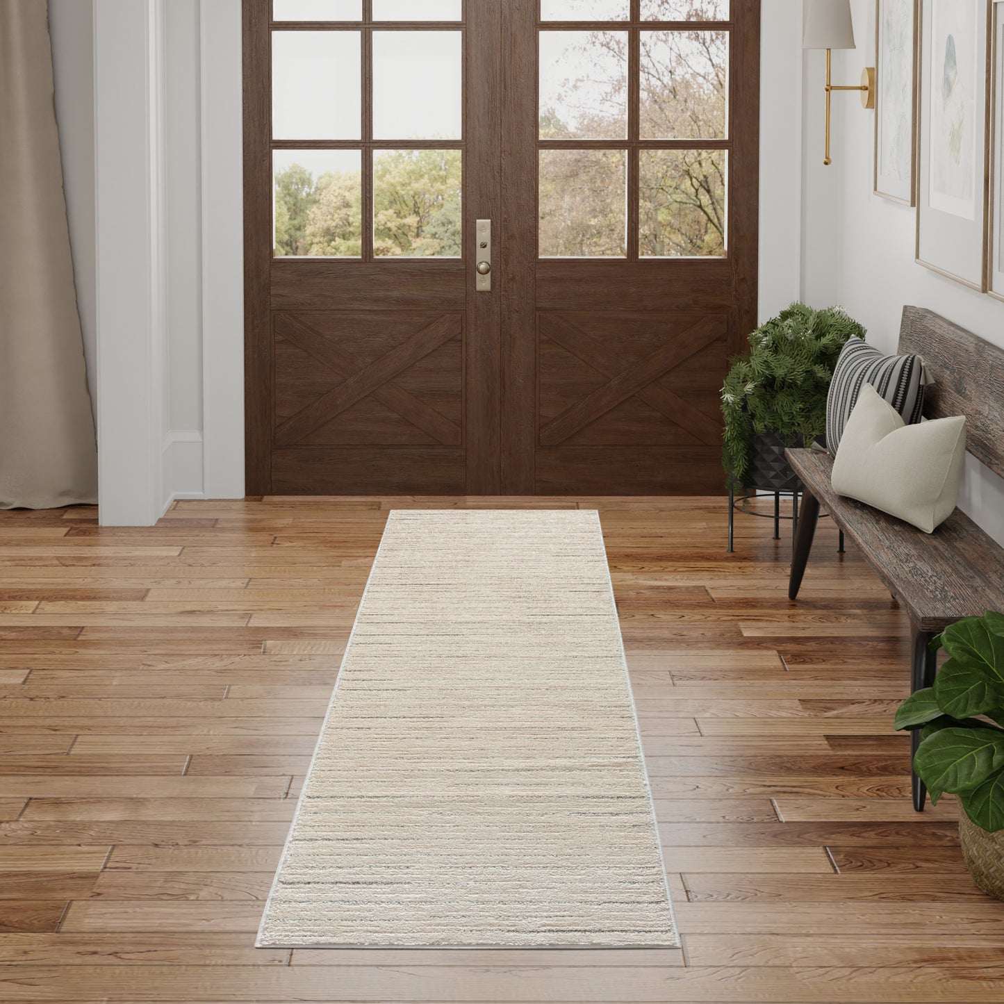 Beige woven 8' runner rug on wood floor in an entry hall with dark wooden double doors, bench and plants.