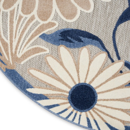 Round rug with cream petals and navy centers in a blue-beige floral pattern on a woven gray base.