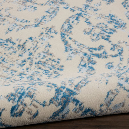 Cream textile with blue distressed damask pattern, folded corner; woven decorative fabric for upholstery or home decor.