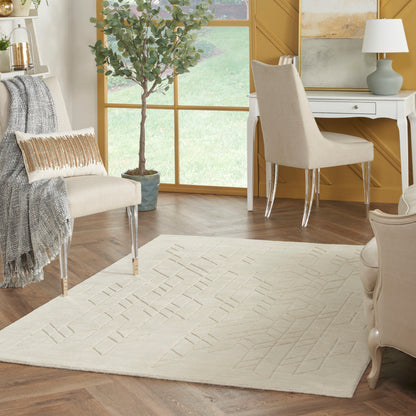 Cream rug with subtle geometric lines on dark wood floor, beige chairs, white desk, potted tree in sunny living room.