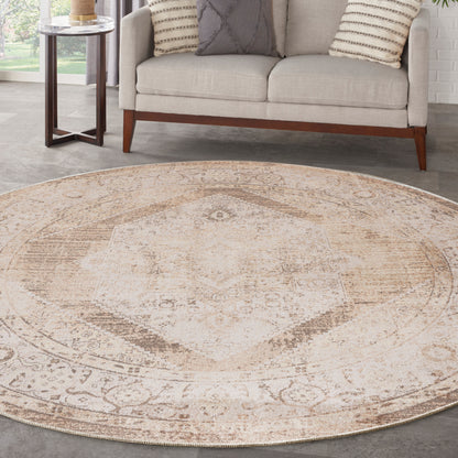 Round beige distressed oriental rug with faded ivory medallion, placed in a living room with a light sofa and wooden legs.