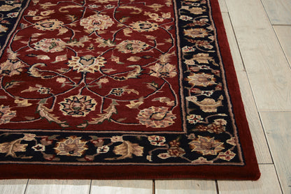 Rectangular oriental rug with deep red field, ivory floral motifs, dark blue border, on light wood floor.