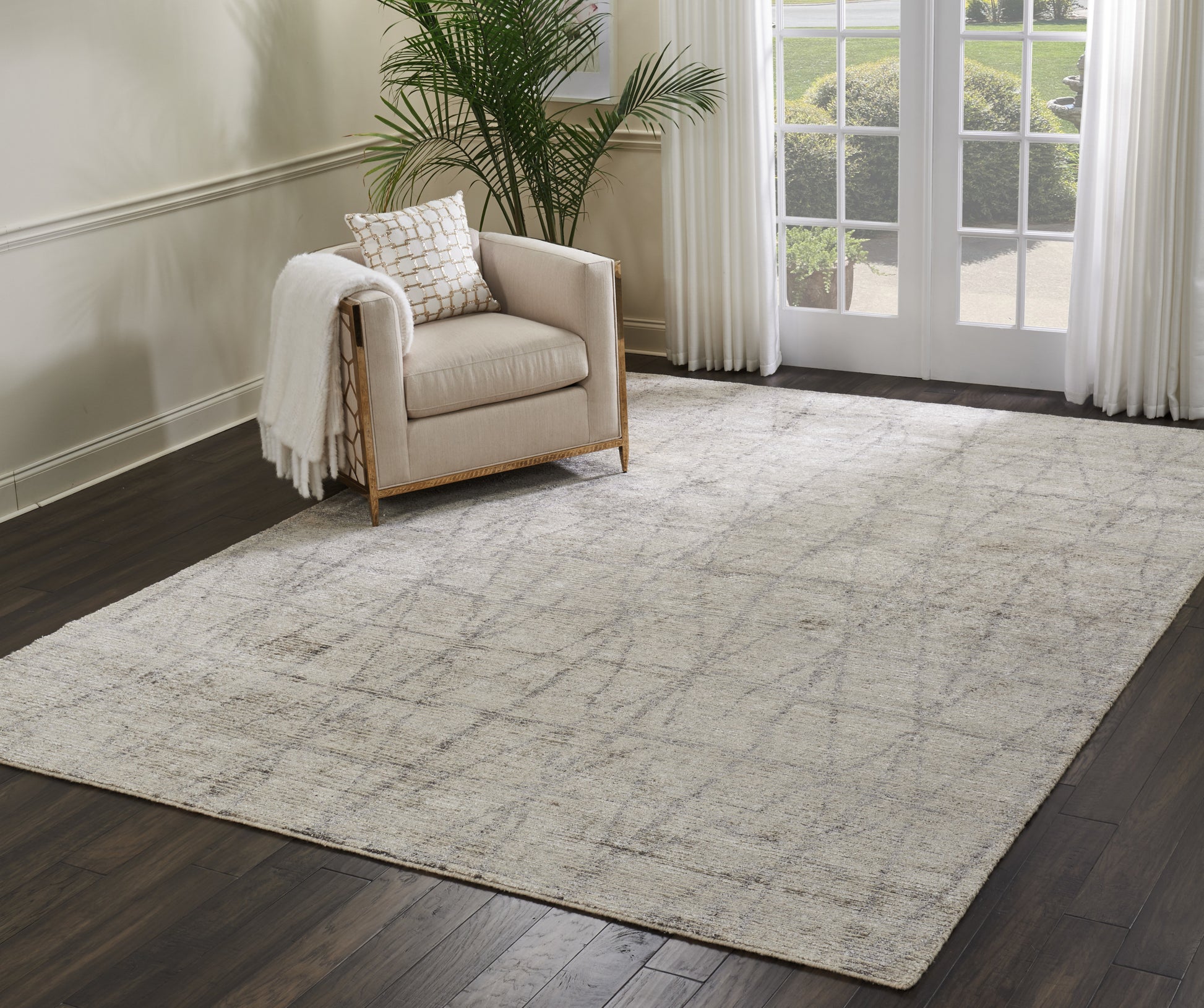 Neutral beige rectangular area rug with subtle grid pattern in a modern living room beside a light armchair and French doors.