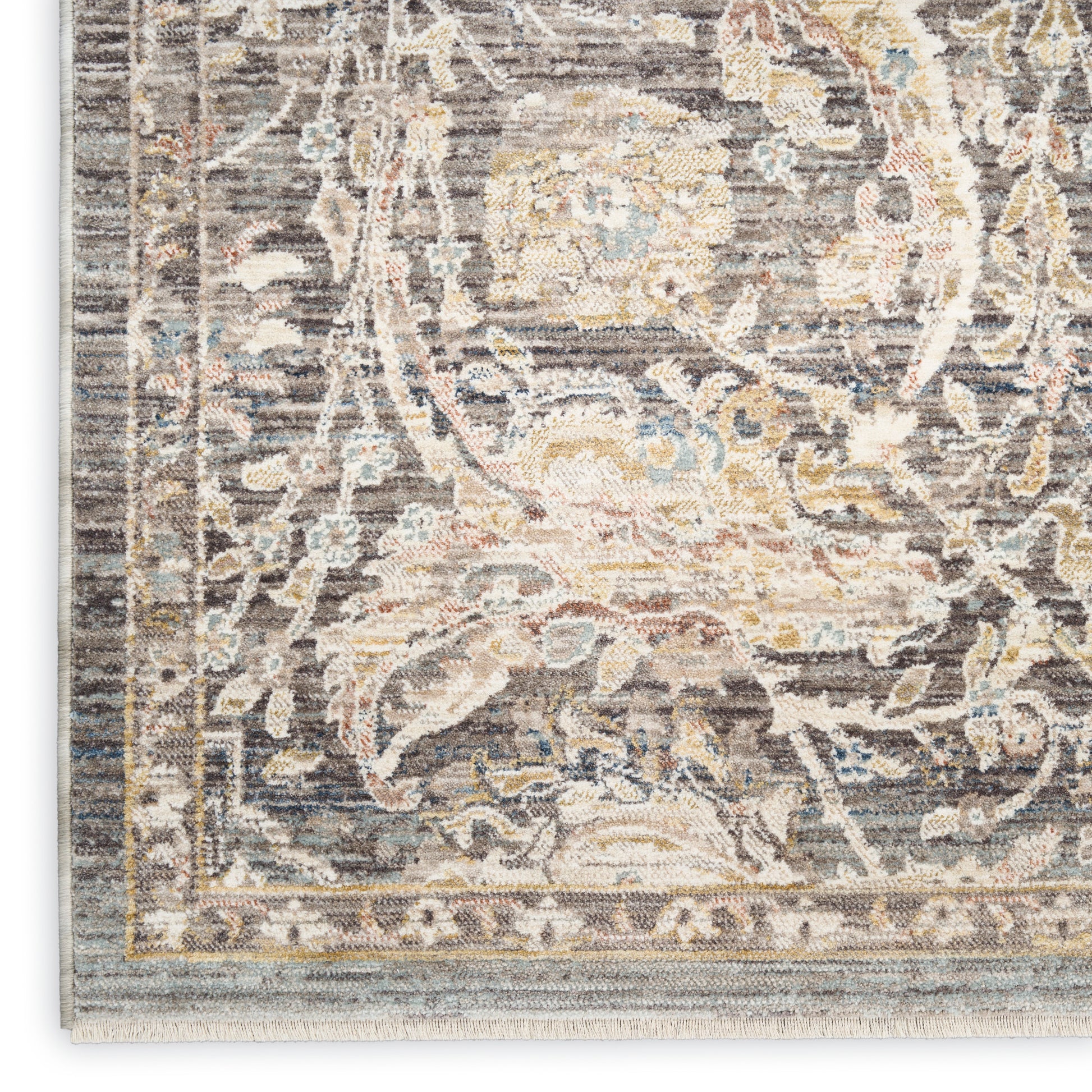 Close-up of a vintage-style floral area rug in gray, ivory, blue and gold with ornate border and distressed texture.