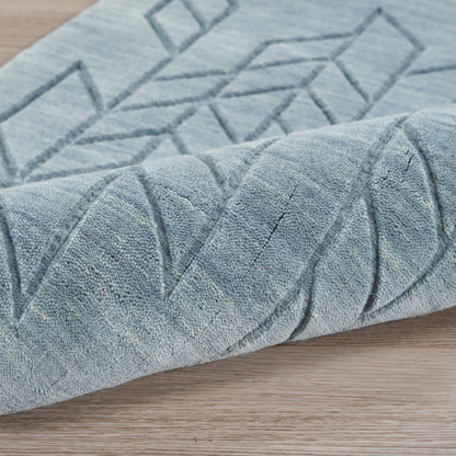 Blue geometric patterned rug with raised diamond lines and soft plush pile, rolled edge on wooden floor.