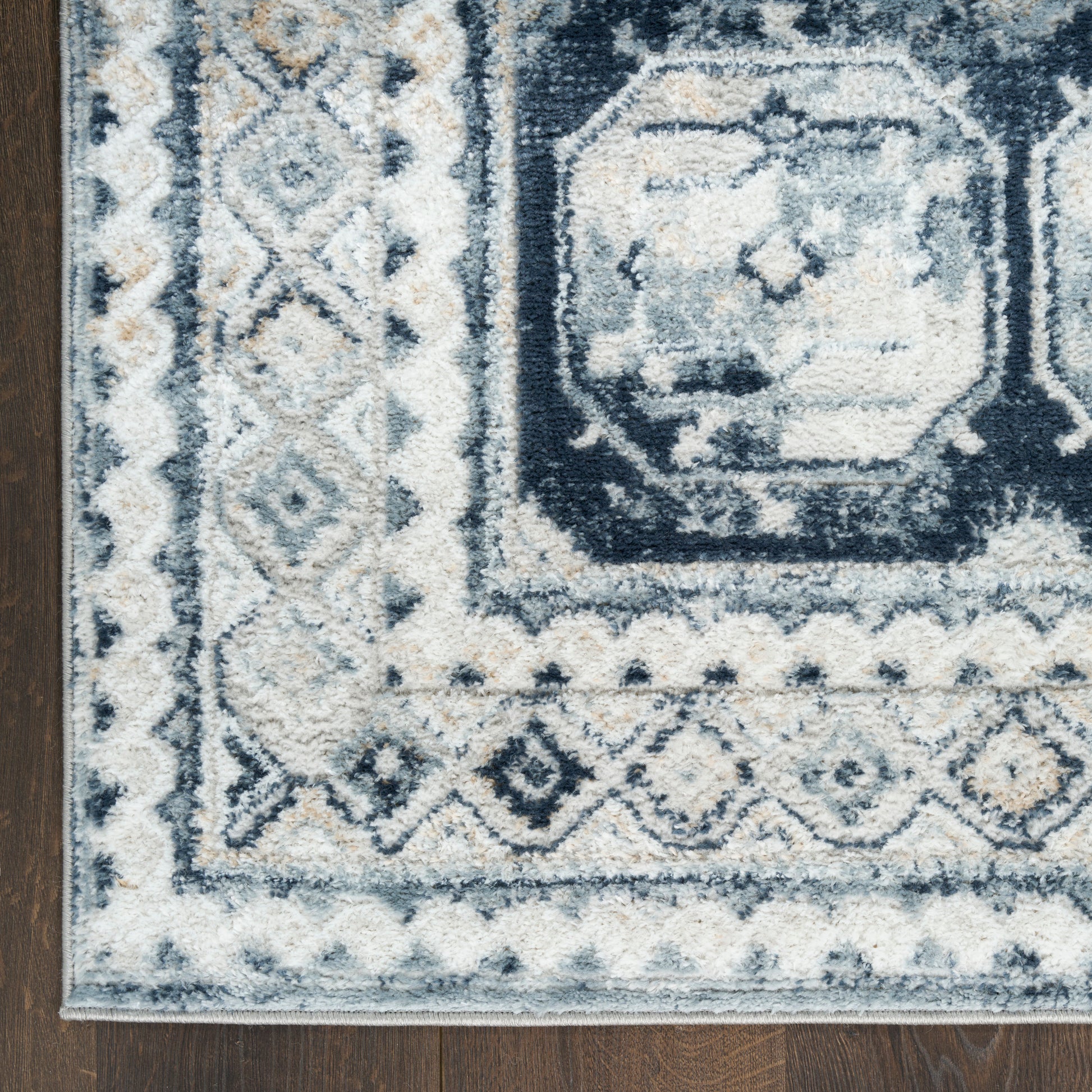 Distressed navy & ivory geometric area rug with diamond border on dark wood floor, vintage 4' X 6'.