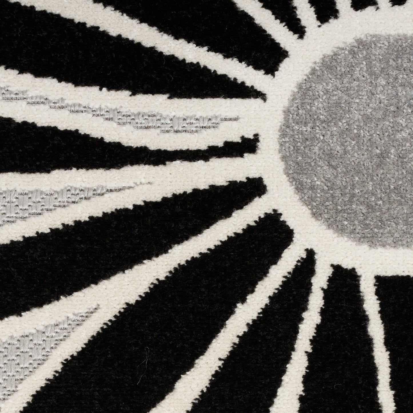 Sunburst rug with black and cream rays and a gray circular center; plush shag texture.