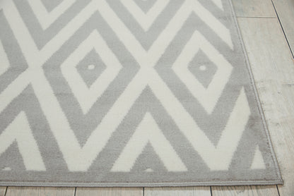 Gray and white geometric chevron rug, low-pile, rectangular, on light wood floor; modern decor.