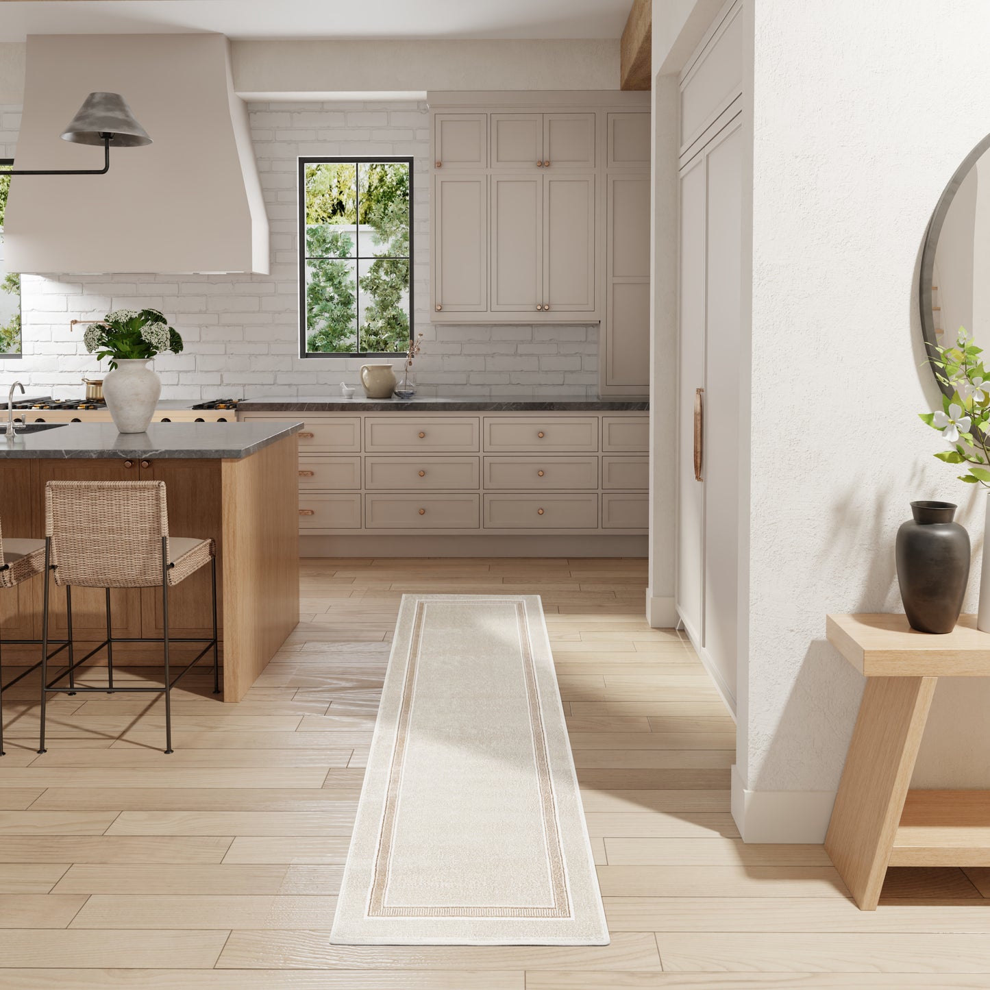 Bright modern kitchen with white shaker cabinets, light wood floors, island with stools, and a long beige runner rug.