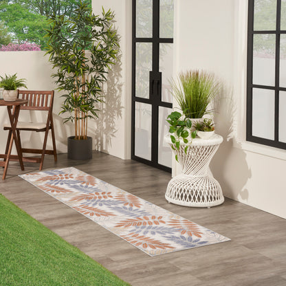 Outdoor 8' runner rug with orange and blue leaf pattern on a light background, placed on a wooden porch.