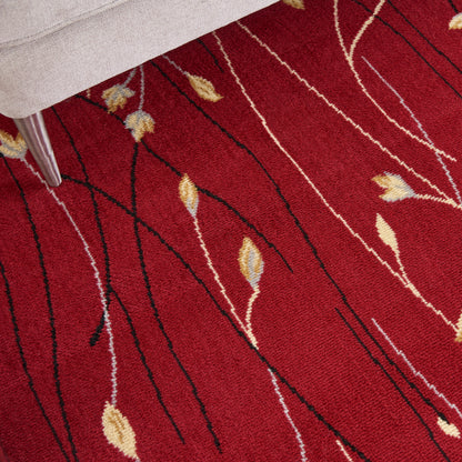 Red area rug with black wavy lines and beige leaf motifs; modern abstract pattern beside a beige sofa.