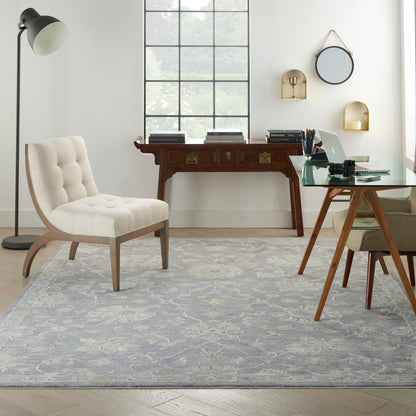 Cream tufted lounge chair with curved wood legs, glass desk, vintage sideboard, gray rug for home office.