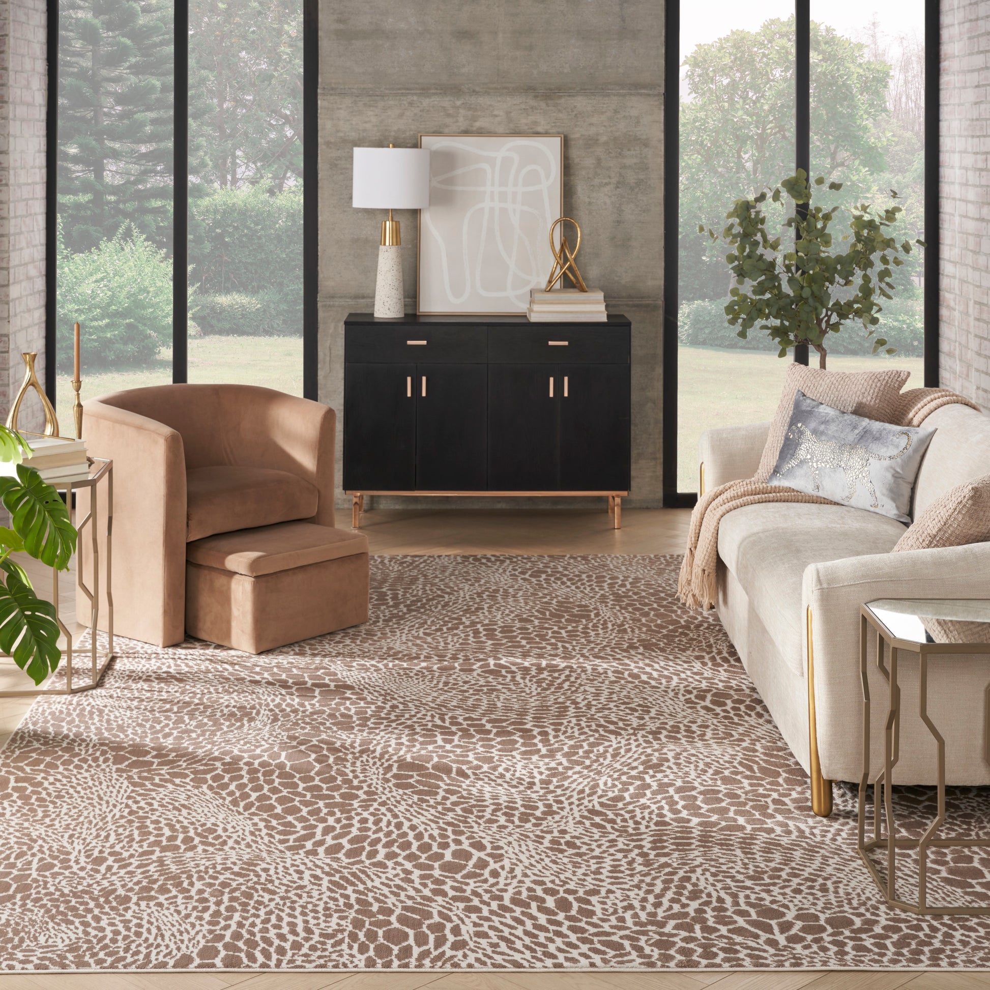 Modern beige living room with peach lounge chair, black sideboard, gold hardware, abstract art, and giraffe-print rug.