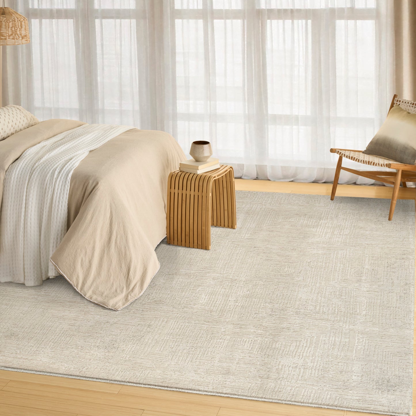 Neutral bedroom with beige bedding, light gray rug, natural wood side table, woven pendant light, and a wooden chair.