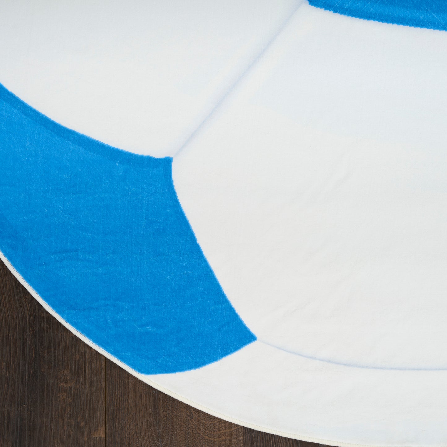 Round area rug with white and cobalt blue curved panels on dark wooden floor.