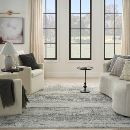 Neutral living room with beige sofas, gray patterned rug, round black coffee table, and large black-framed windows.
