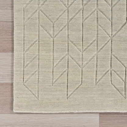 Beige flat-weave area rug with taupe geometric chevron pattern on wood floor.
