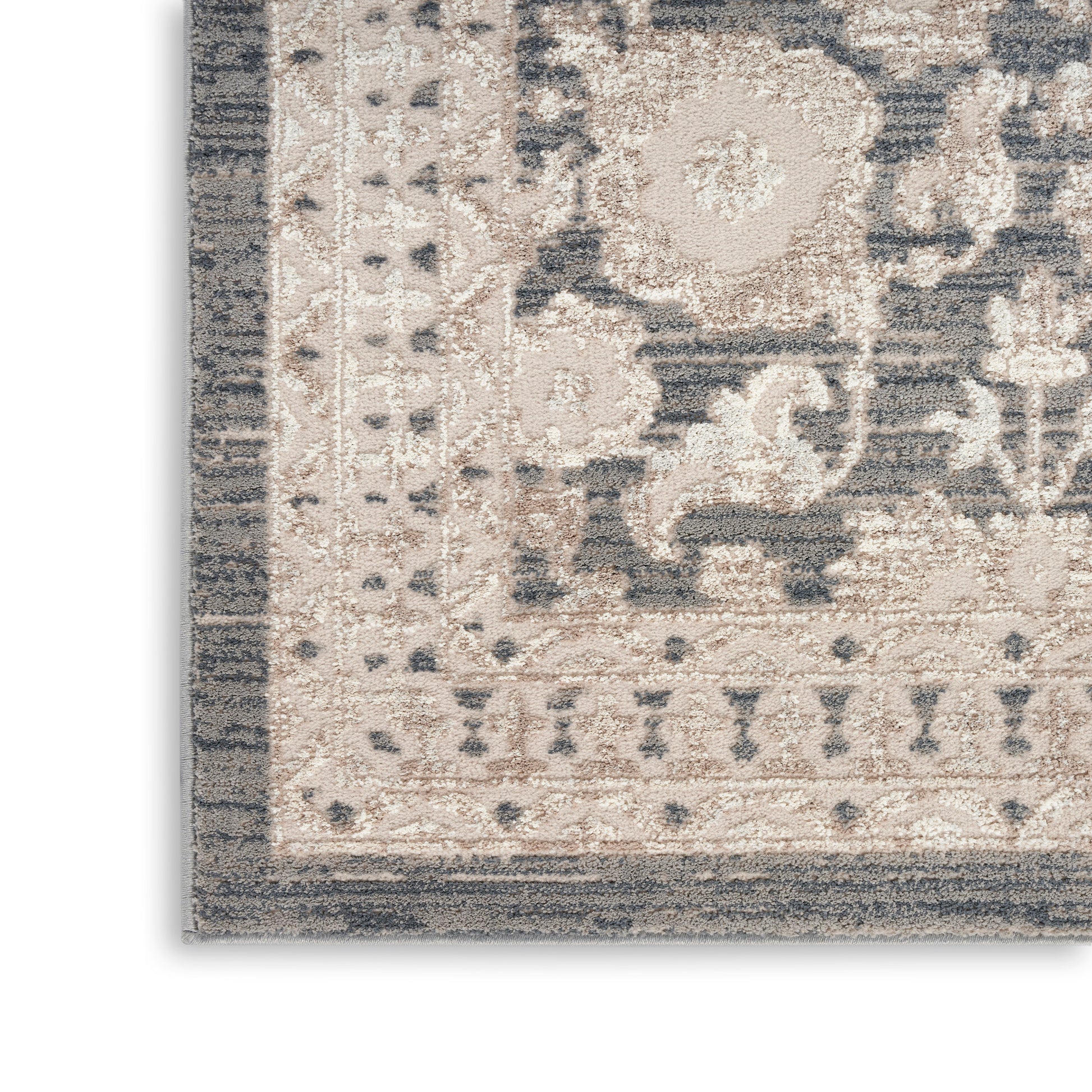 Beige & gray distressed oriental area rug corner with ornate floral border, plush pile, neutral tones