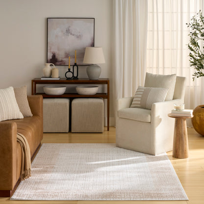 Neutral living room with tan leather sofa, cream armchair, light rug, wooden console, two woven ottomans, abstract art.