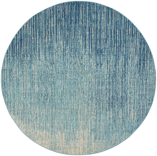 Round rug with blue gradient and vertical stripe texture, navy to beige ombre.