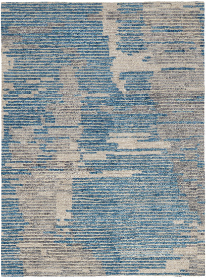 Rectangular area rug featuring an abstract blue and beige distressed pattern; modern woven texture.
