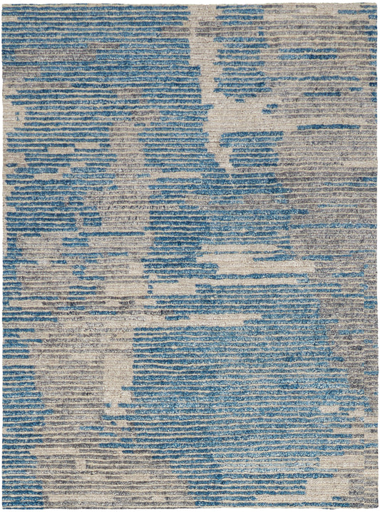 Rectangular area rug featuring an abstract blue and beige distressed pattern; modern woven texture.
