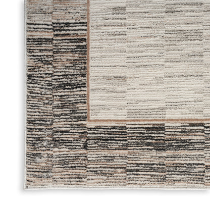 Neutral-toned rectangular area rug with patchwork striped pattern in beige, cream, taupe and brown; textured woven surface.