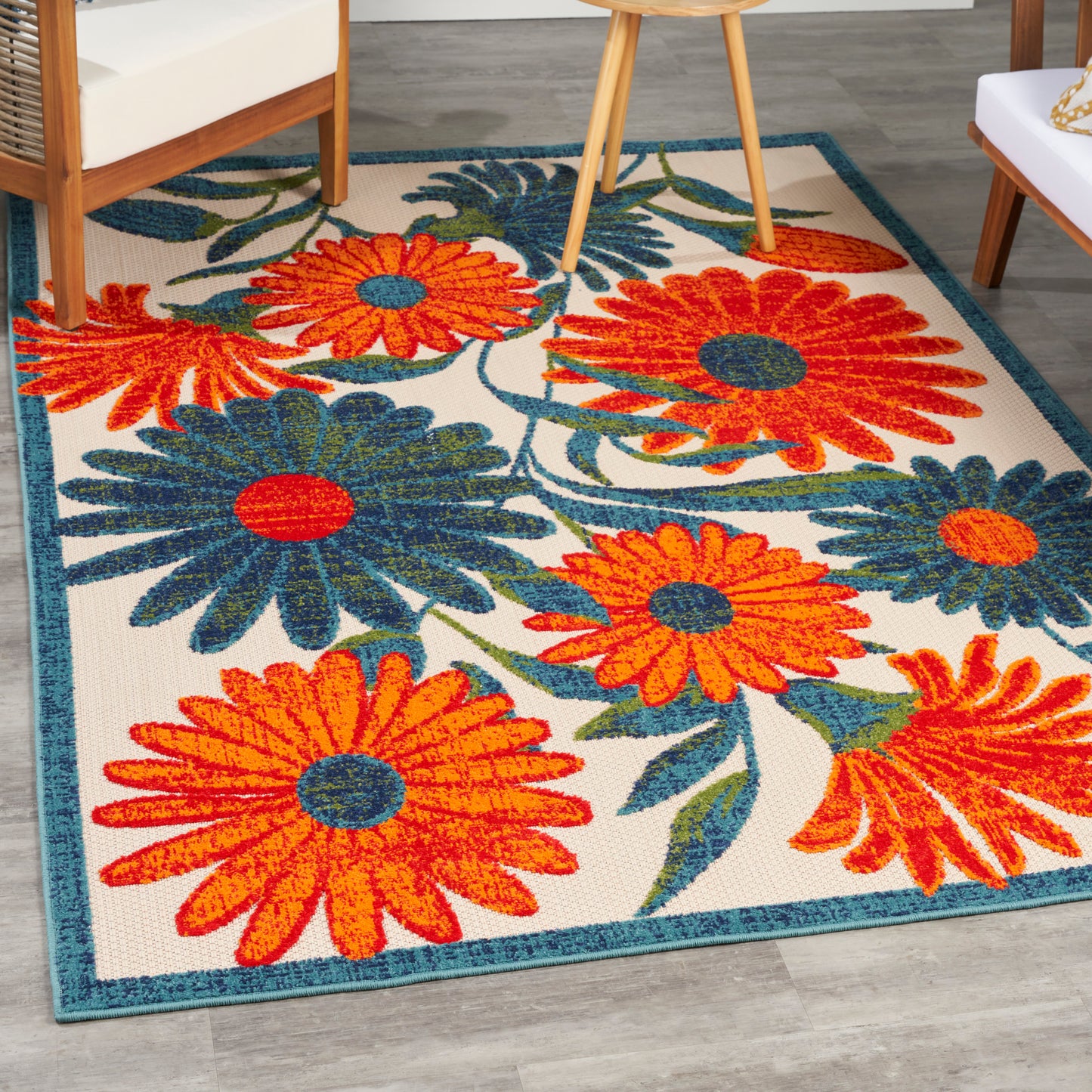 Bright outdoor rug with an oversized orange and blue floral print, teal border, and beige background; size 4' x 6'.