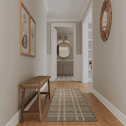 Neutral entryway with wooden bench, woven seat, geometric runner, wicker round mirror, framed art; opens to bathroom vanity.