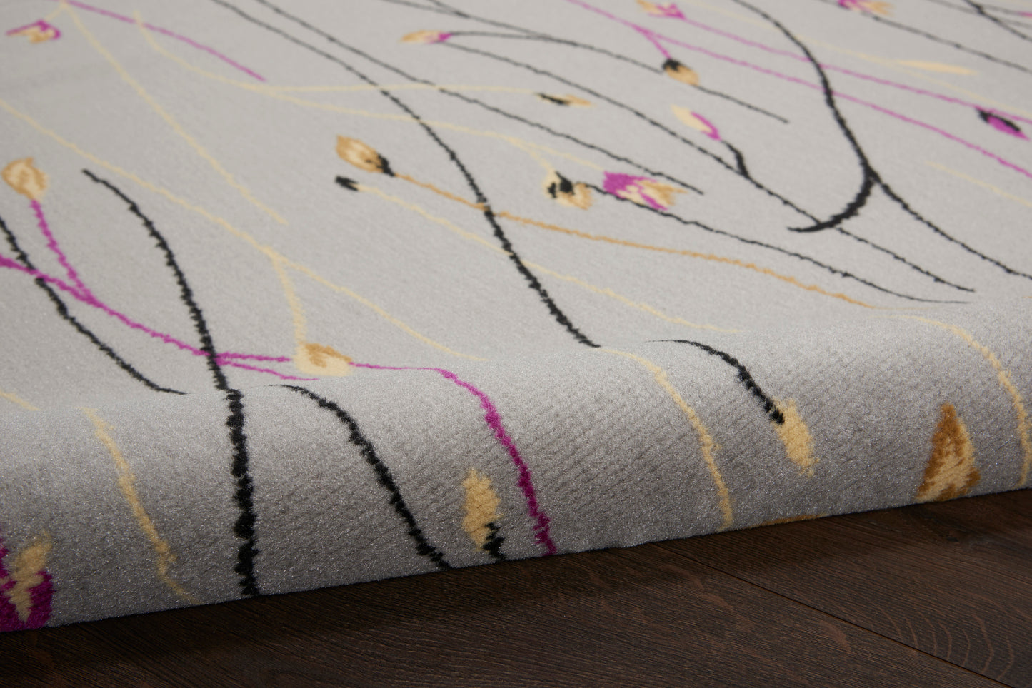 Gray rug with abstract multicolor curved lines in black, pink, yellow and beige; plush pile.