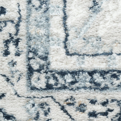 Close-up of a cream shag rug with blue-gray geometric border and plush texture.