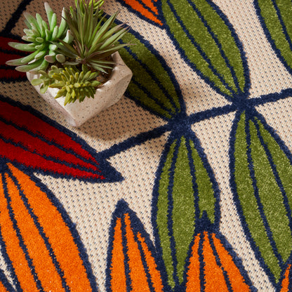 Beige woven rug featuring bold orange, green, and blue tropical leaves; small succulent pot rests on edge.