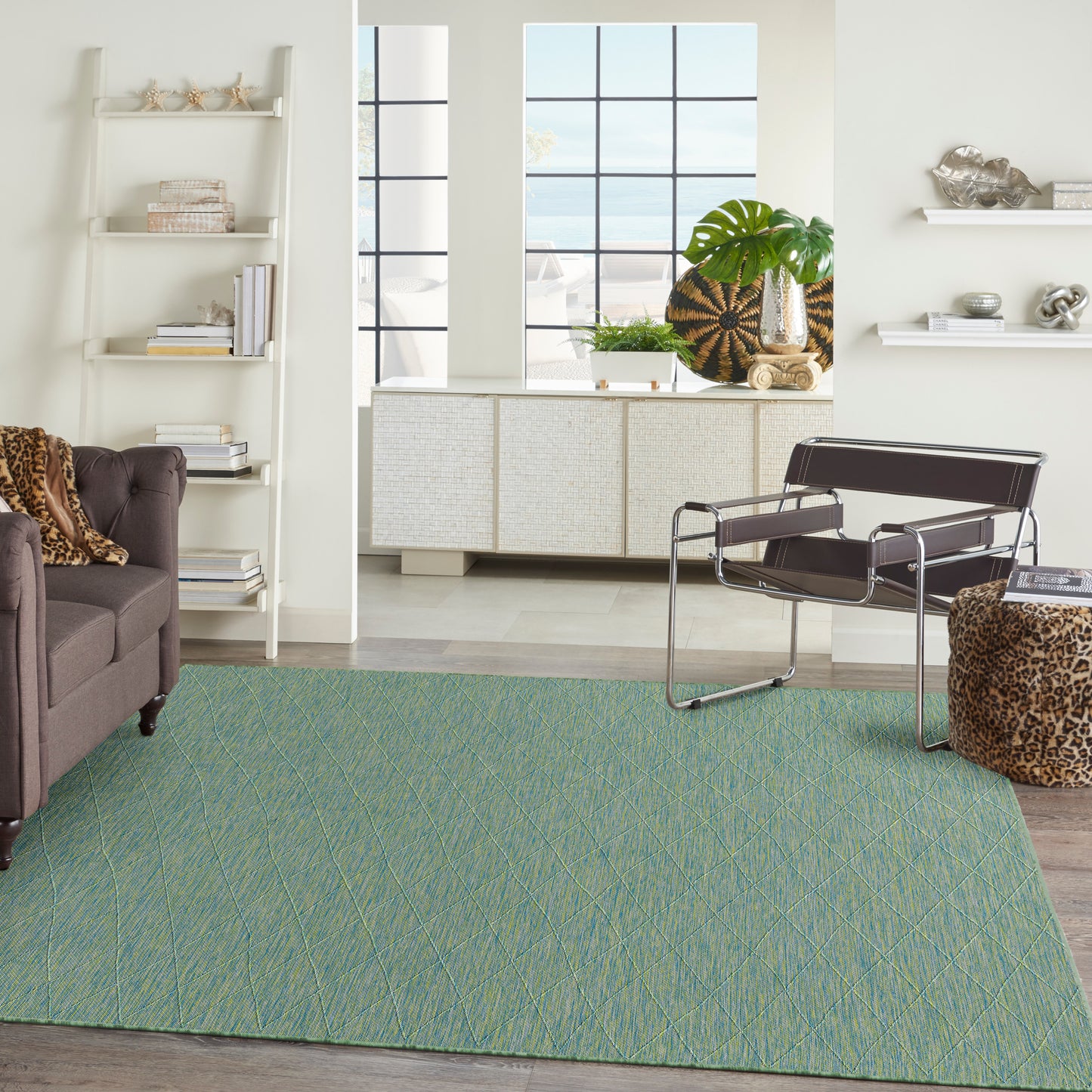 Teal geometric area rug with diagonal lattice in living room; brown tufted sofa and black leather & chrome lounge chair.