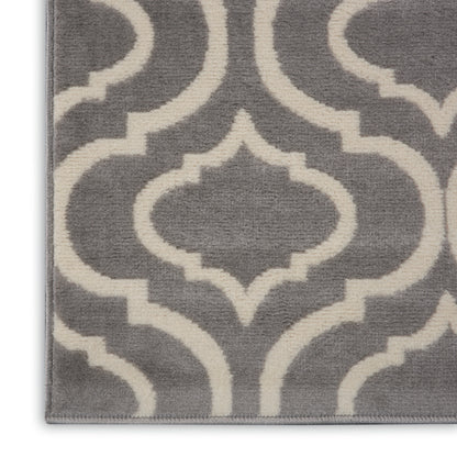 Grey plush area rug with ivory Moroccan trellis pattern and bound edges.