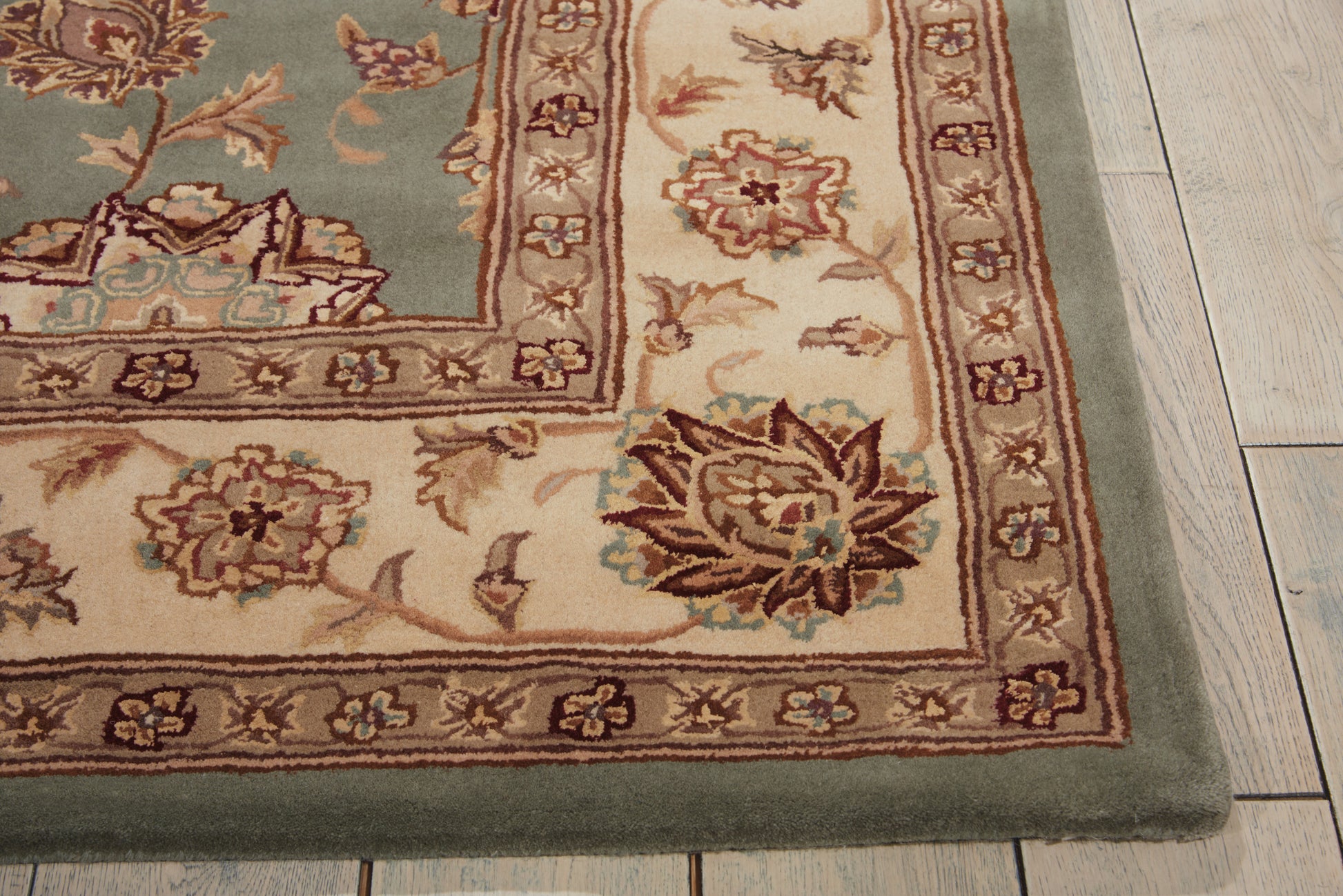 Teal oriental area rug, woven, with cream & brown floral border & green outer edge.