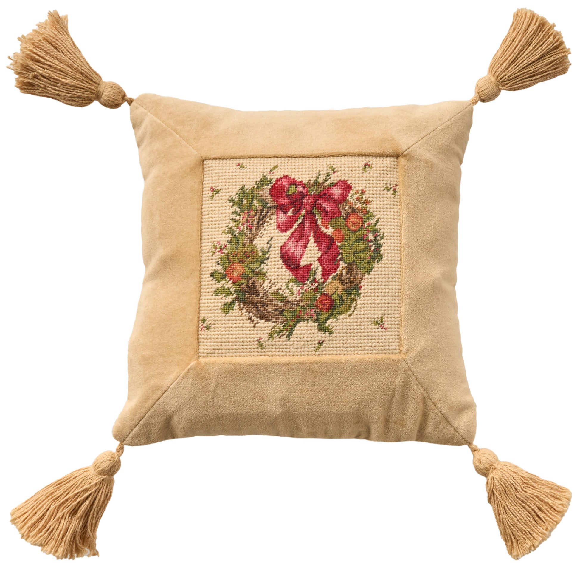 Beige square throw pillow with cross-stitched wreath and red bow, tassels at all four corners.