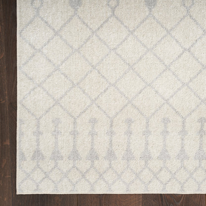 Cream rug with pale blue lattice diamonds and an arched border along the bottom edge, on a dark wood floor.