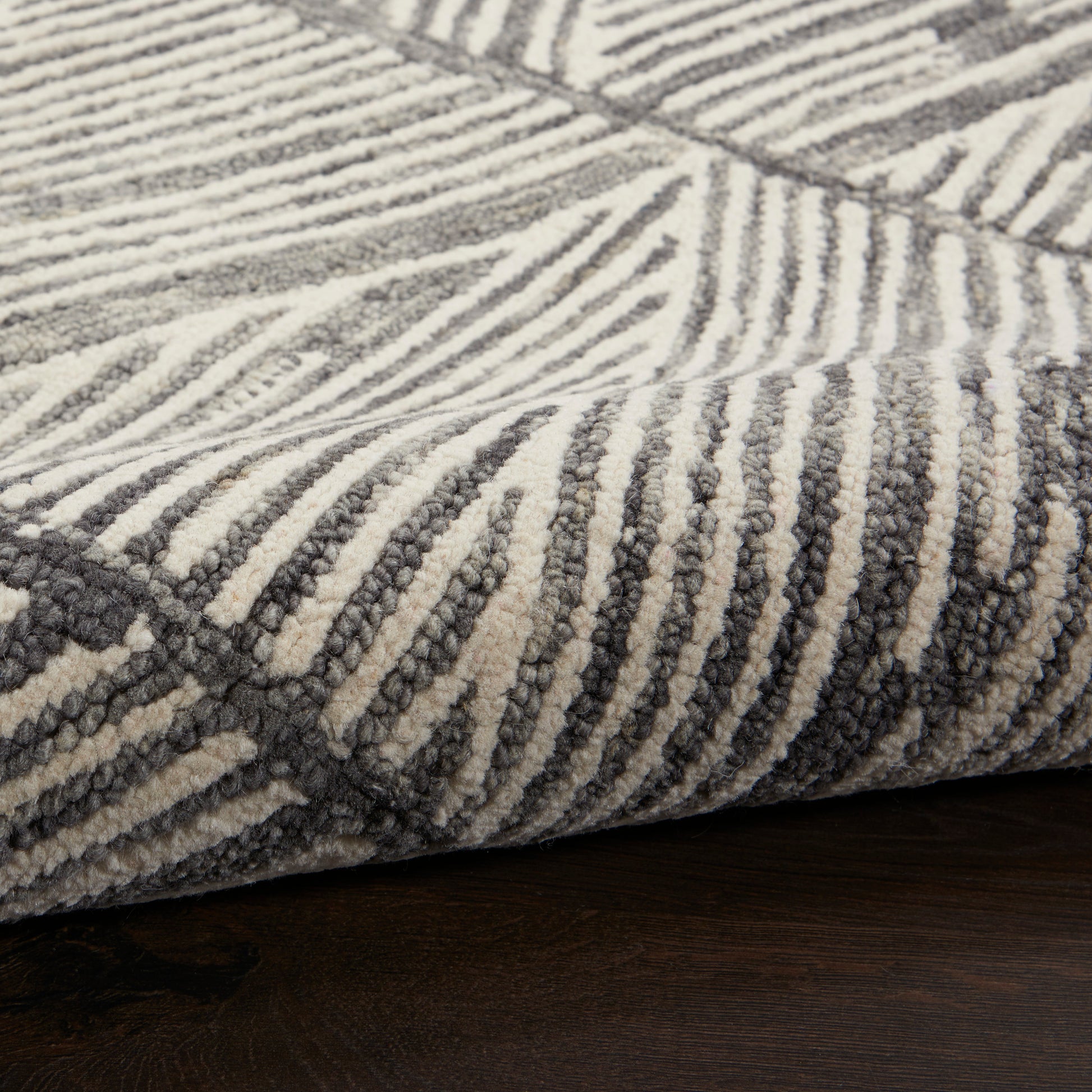 Close-up of a plush cream and charcoal gray striped area rug with a thick pile on a dark wood floor.