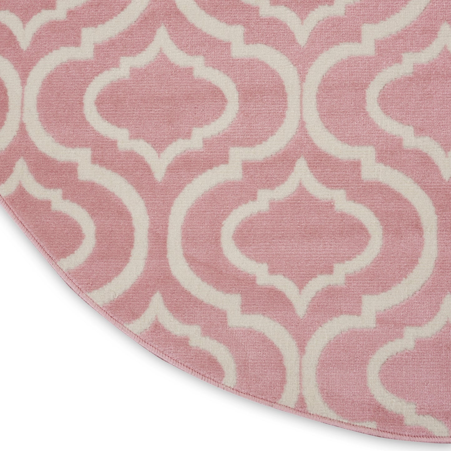 Round pink rug with white Moroccan trellis pattern.