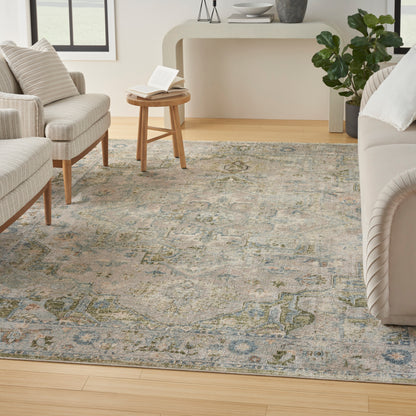 Muted blue-gray oriental rug with beige and green motifs in a bright living room with cream seating and wood furniture.
