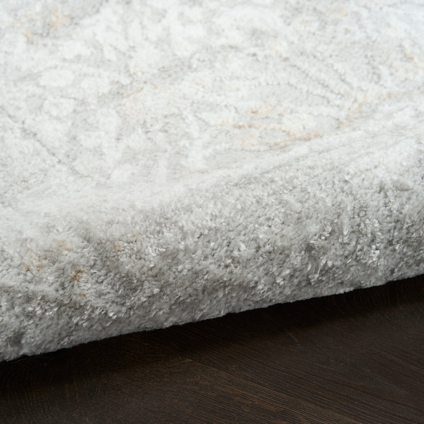 Rectangular light gray shag rug with plush pile on dark wood floor.