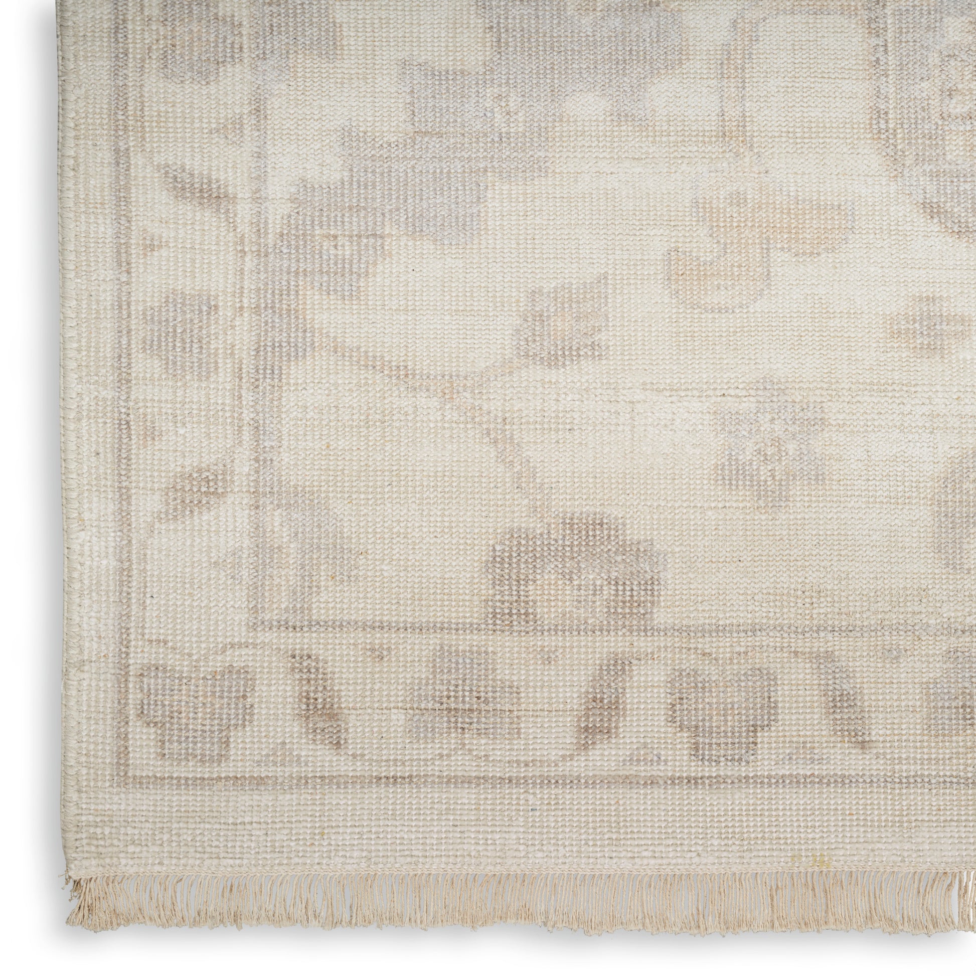 Cream woven rug with subtle taupe floral border and fringe along bottom edge.