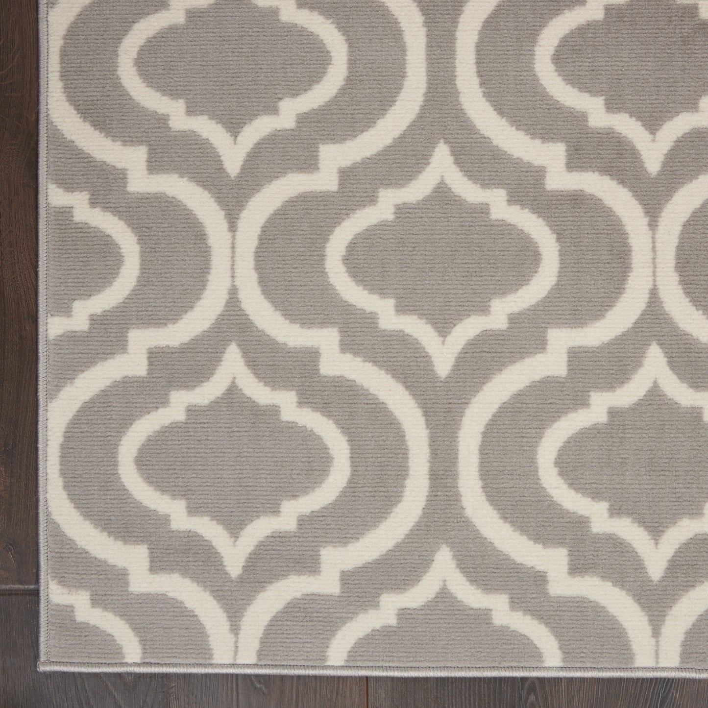 Gray flat-weave rug with white interlocking trellis pattern; rectangular, modern geometric decor.