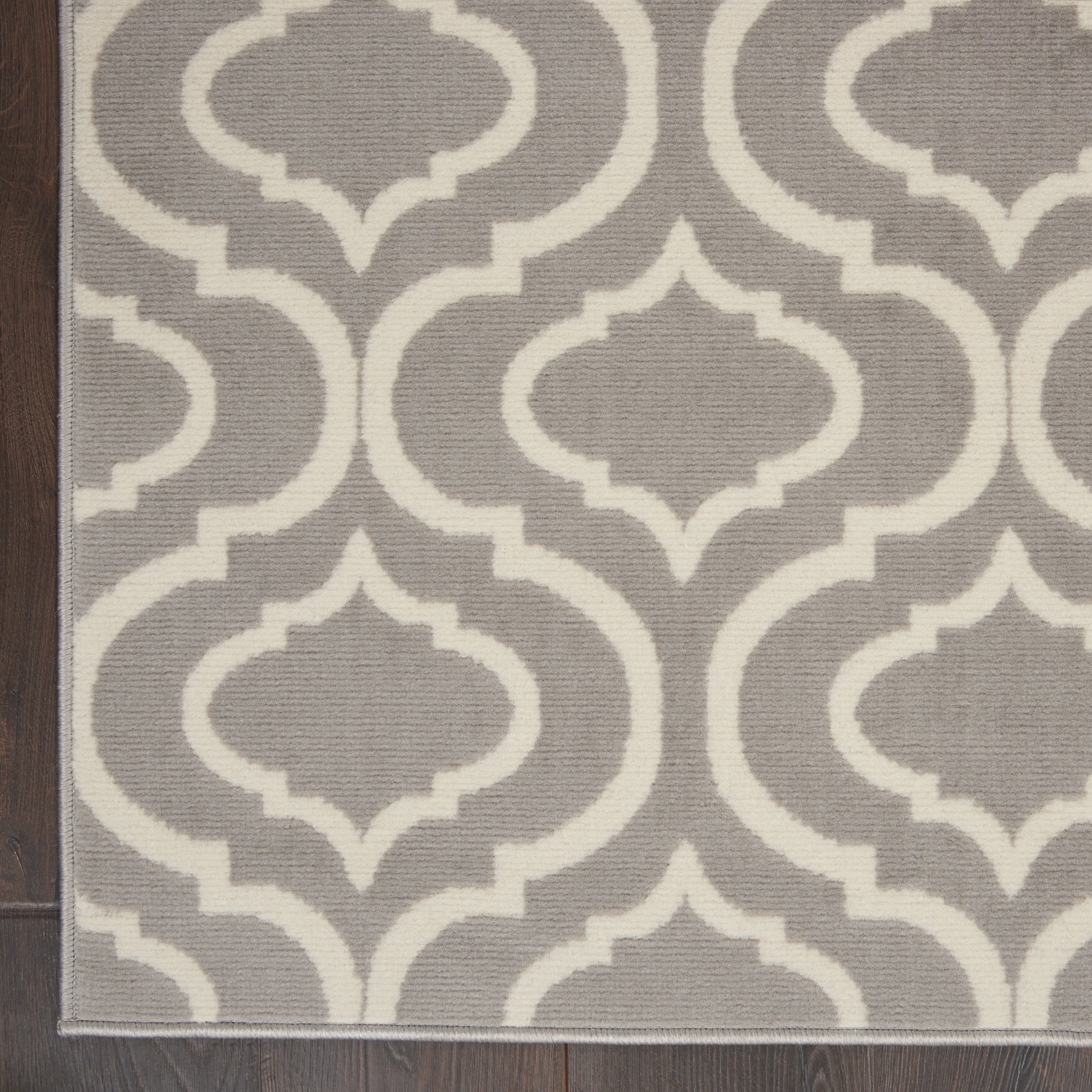 Gray flat-weave rug with white interlocking trellis pattern; rectangular, modern geometric decor.